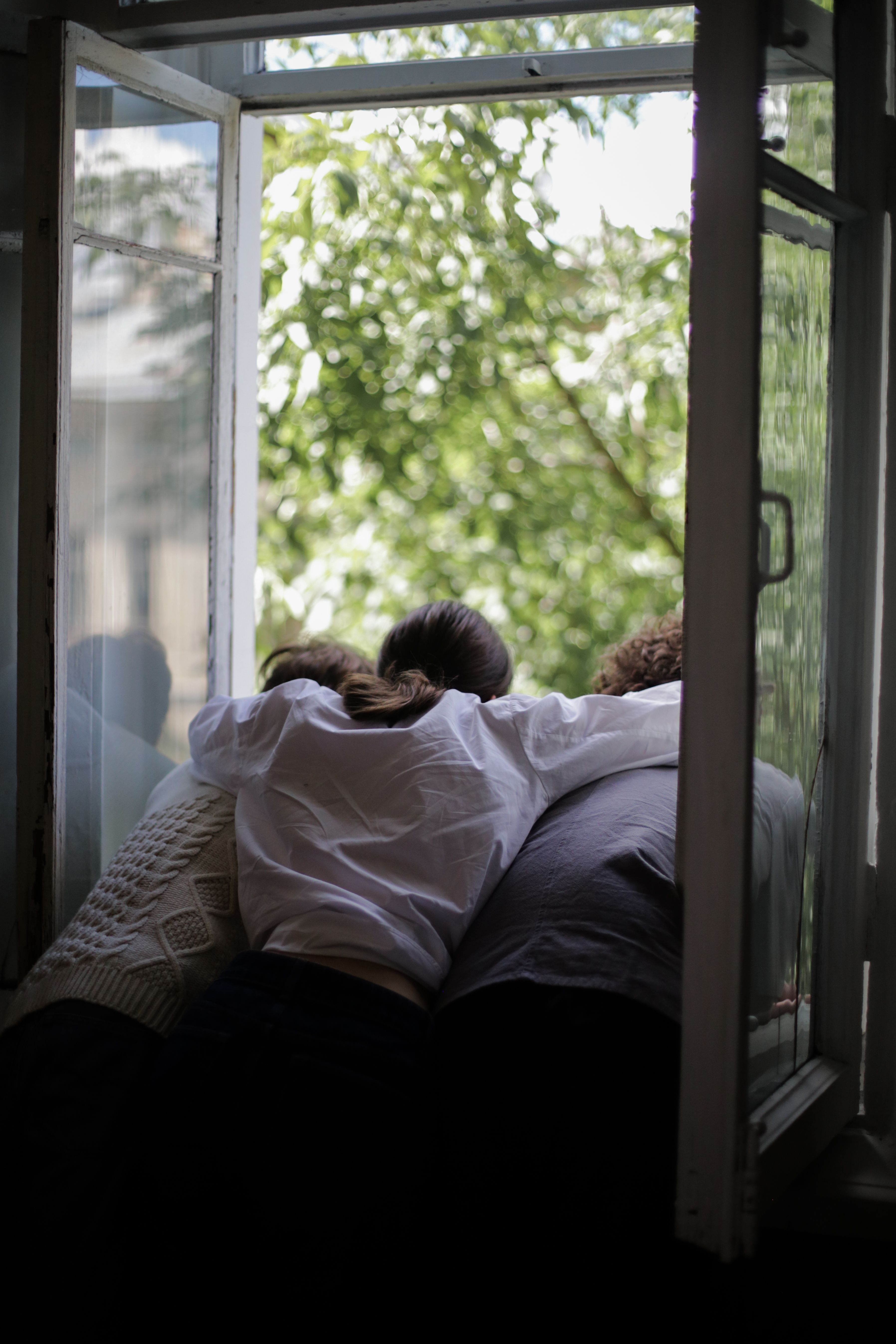 τρία άτομα γυρισμένα πισώπλατα κοιτούν αγκαλιασμένα έξω από το παράθυρο
